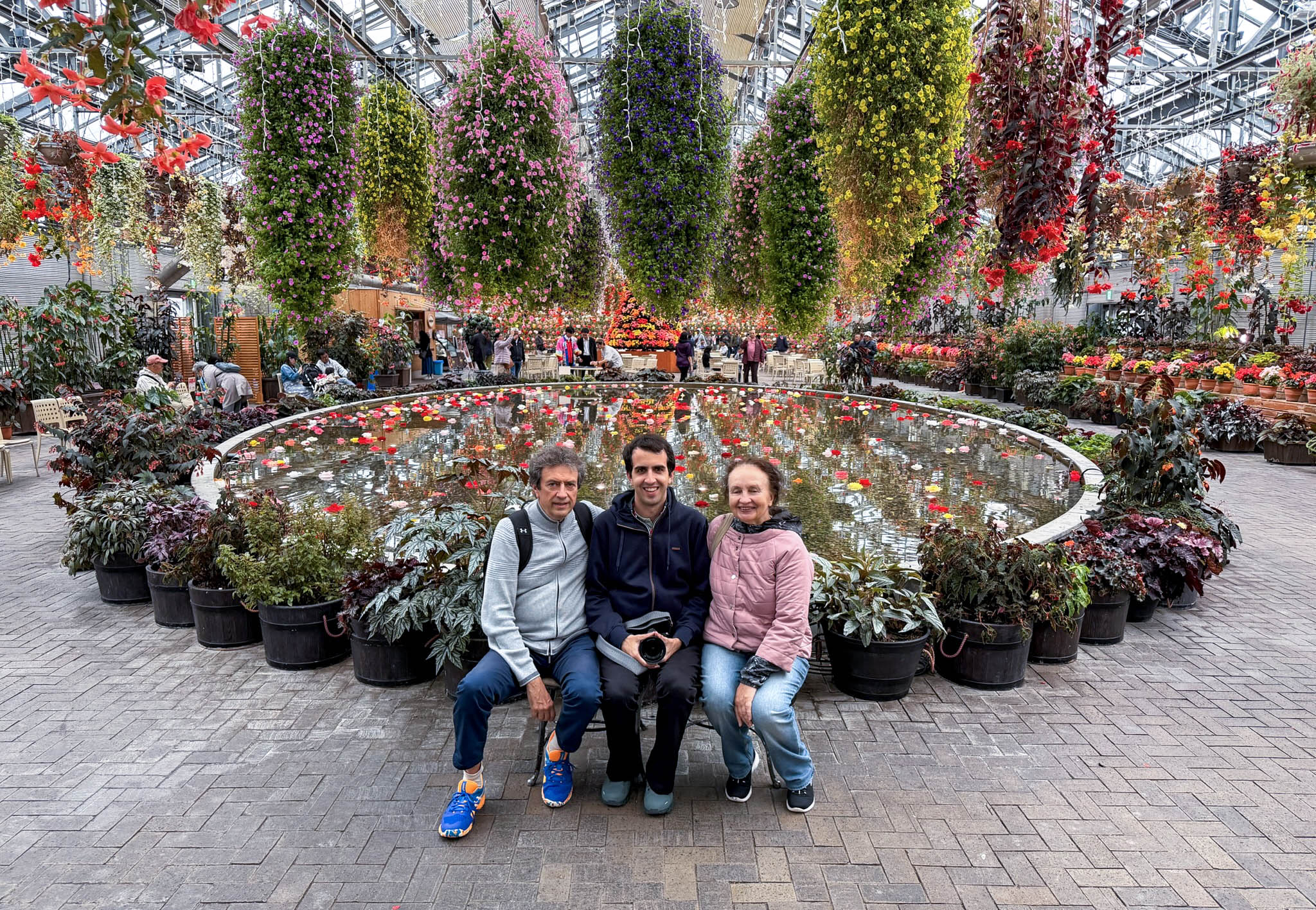 Vadim and his parents sitting in front of a flower display.
